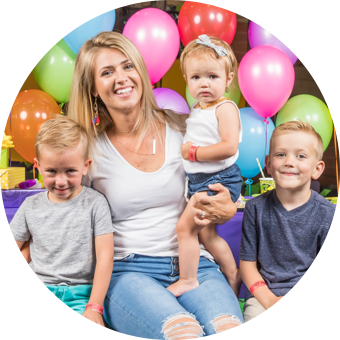 Smiling woman with three children and balloons.