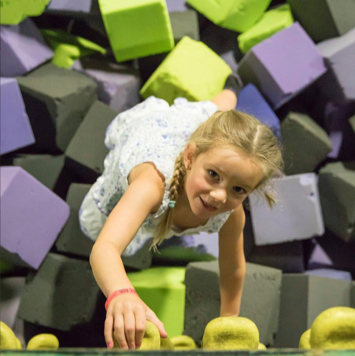 Girl climbing a rock wall in foam pit.