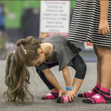 Girl putting on pink Get Air socks.