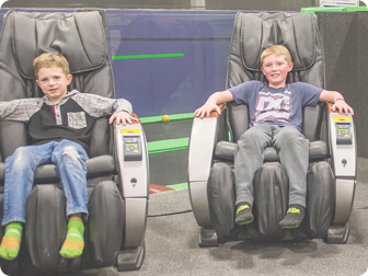 Two boys relaxing in massage chairs.