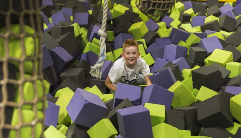 Smiling boy crawling through a foam pit.