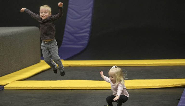 Two young children jumping on trampolines.