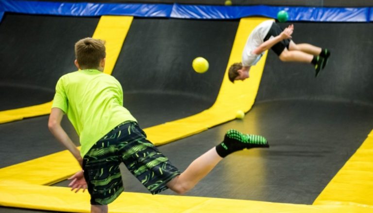 Two boys playing dodgeball on trampolines, one boy mid-flip.