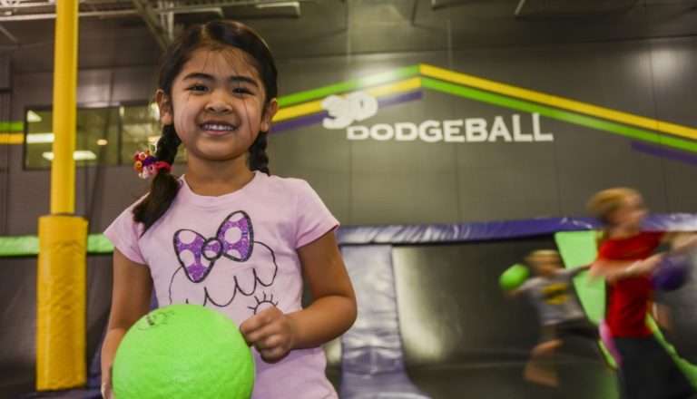 Smiling girl holding a dodgeball at Get Air.