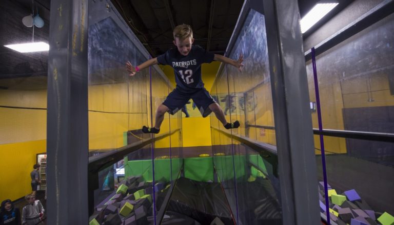 Boy stretching between two walls over a foam pit.