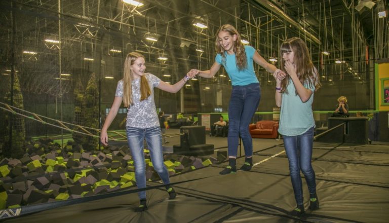 Girls holding hands on slacklines.