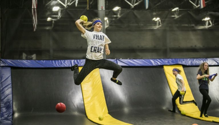 Girl playing dodgeball, mid-jump, at Get Air.