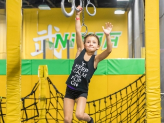 Girl swinging on rings at the Get Air ninja course.