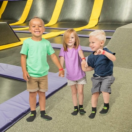 Three kids holding hands and smiling at Get Air.