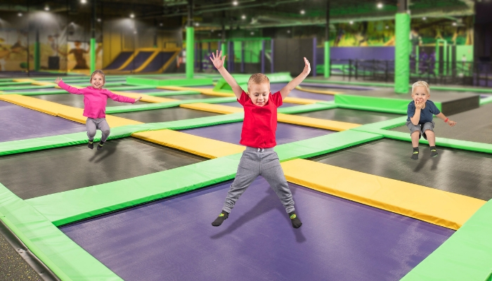 Kids happily jumping on trampolines.