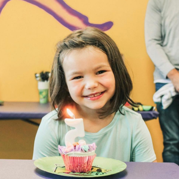 Girl with cupcake celebrating 5th birthday.