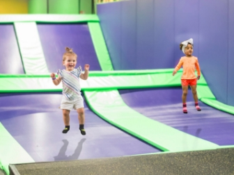 Two toddlers jumping on indoor trampolines.