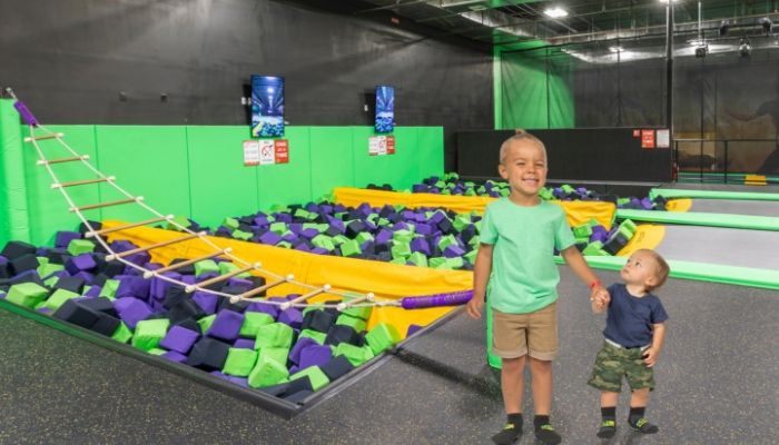 Two kids standing near a foam pit.