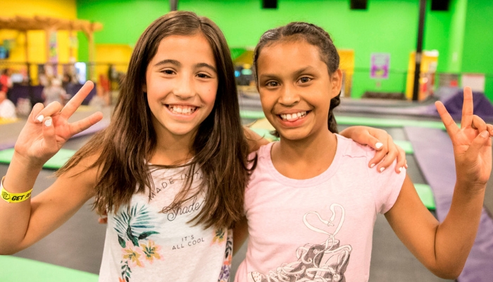 Two girls smiling and showing peace signs.